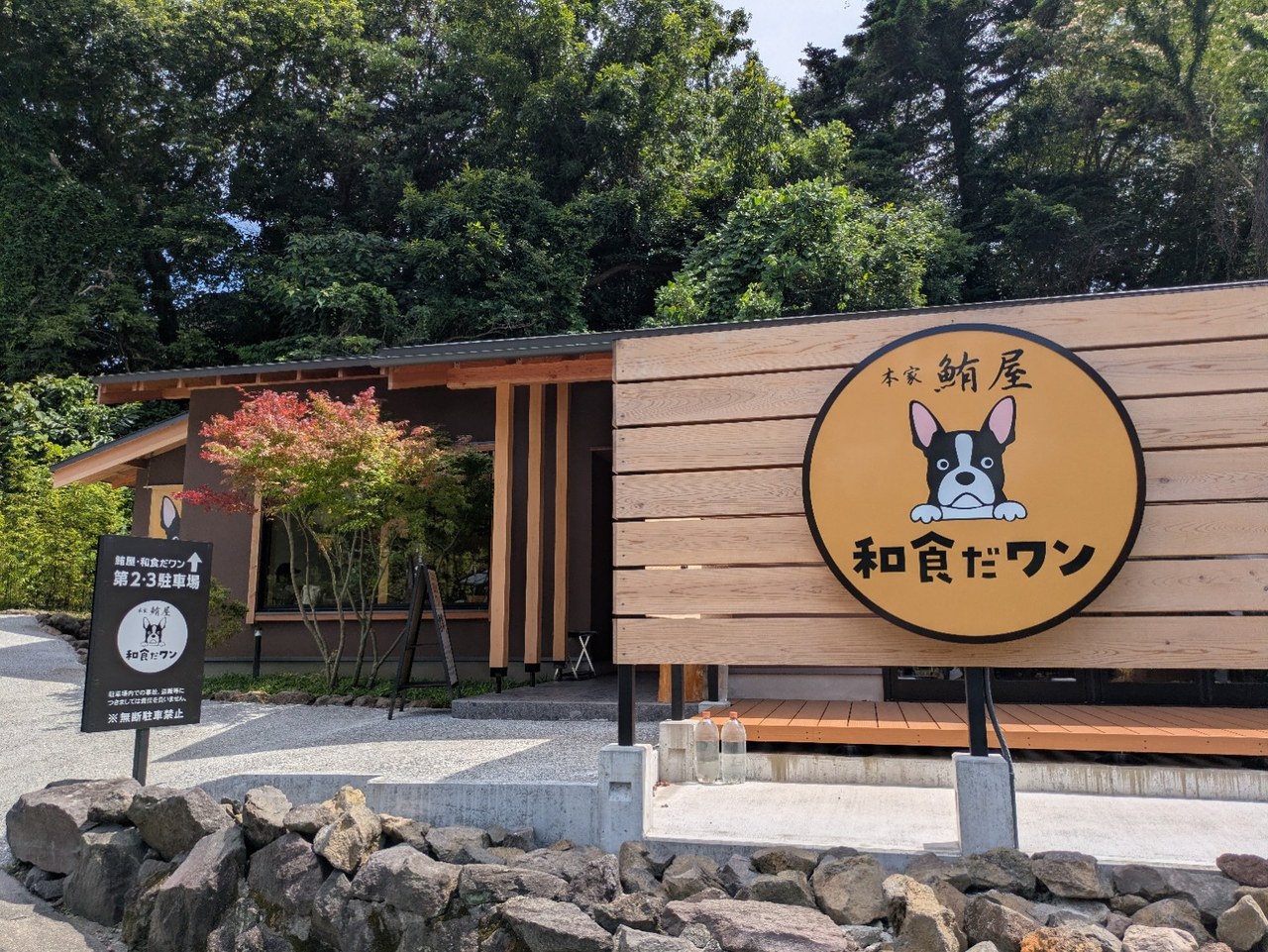 木塀の和食だワンの丸い店舗看板と、左側に立つ第2・第3駐車場の案内看板