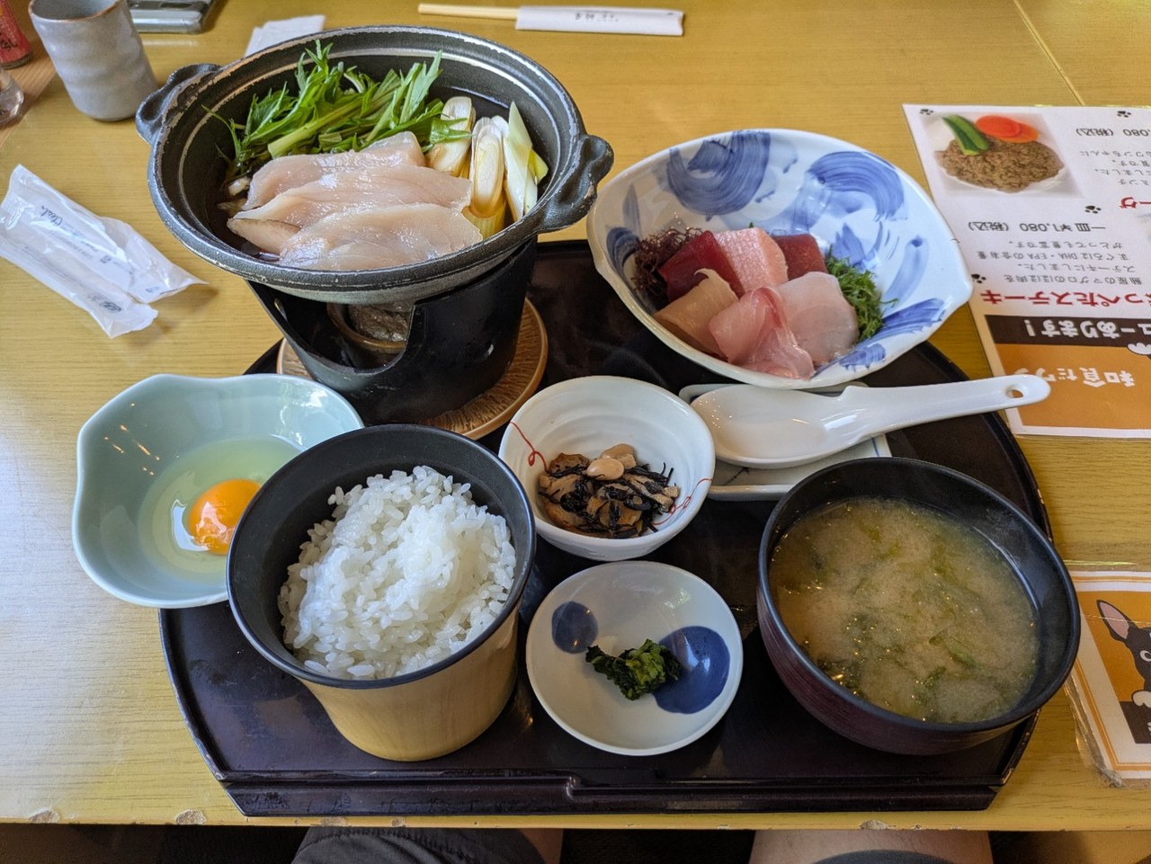 マグロと野菜の小鍋、刺身、ご飯、生卵、小鉢、味噌汁が並ぶ御膳